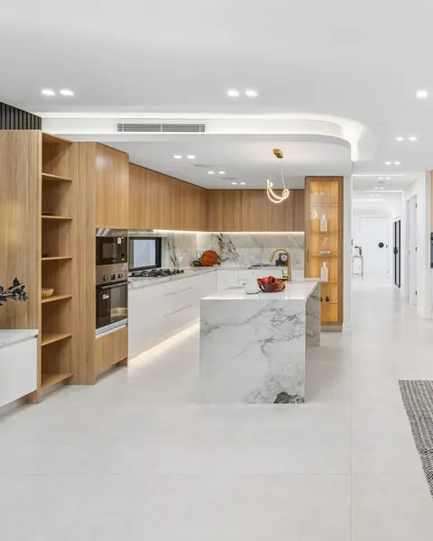 Kitchen with timber joinery and a marble waterfall island, in a knockdown rebuild in Chipping Norton by St Anthony Building Group