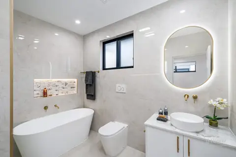 Bathroom with freestanding bath and backlit round mirror – knockdown rebuild at 28 Aylesbury Crescent, Chipping Norton